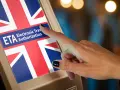 Palec dotyka ekranu z napisem ETA Electronic Travel Authorization i flagą Wielkiej Brytanii. Zastanawiasz się, ile kosztuje ETA do UK?