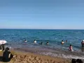 Słoneczny dzień na plaży Lara. Ludzie kąpią się w turkusowym morzu, inni odpoczywają na piaszczystym brzegu.