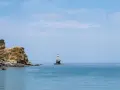 Widok na morze z latarnią morską na skale i zabudowaniami na klifie na wyspie Andros.