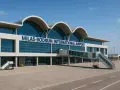 Nowoczesny budynek lotniska Milas-Bodrum International Airport z charakterystycznymi łukami dachu i przeszkloną fasadą.