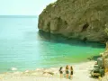 Trzy dziewczyny idą plażą w Grecji, ciesząc się słońcem i turkusową wodą. Idealne miejsce na tanie wakacje w Grecji.
