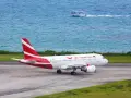 Samolot Air Mauritius na pasie startowym, w tle turkusowe morze i łódź. Twoje loty na Mauritius właśnie się zaczynają!