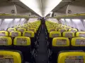 Puste rzędy żółtych siedzeń w samolocie Ryanair. Widać instrukcje bezpieczeństwa na oparciach.