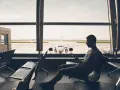 Mężczyzna czeka na lotnisku, patrząc na samolot. To widok z jednego z największych lotnisk w Polsce.