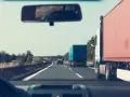 Jadąc autostradą, zastanawiam się, jakie kraje obejmuje zielona karta ubezpieczenia. W lusterku widzę inne ciężarówki.