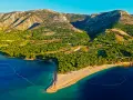 Idealne miejsce, gdzie na wakacje w lipcu: piaszczysta plaża w kształcie rogu obfitości, otoczona zielonymi wzgórzami i krystalicznie czystym morzem.