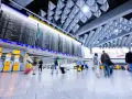 Lotnisko, tablica odlotów, ludzie z bagażami. "Boarding co to?" - to informacja o wejściu na pokład samolotu.