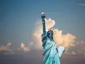 Statua Wolności z pochodnią w górze, symbol USA. Planujesz podróż? Pamiętaj o ubezpieczeniu turystycznym USA.