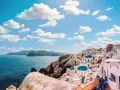 Santorini, Grecja. Białe domy z niebieskimi kopułami na klifie nad morzem. Zastanawiasz się, ile się leci do Grecji?