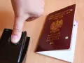 Palec na czytniku linii papilarnych obok polskiego paszportu. To pokazuje, ile ważny jest paszport w dzisiejszych czasach.