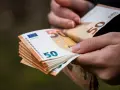 Dłonie trzymają stos banknotów 50 euro. Choć Bułgaria ma swoją walutę, euro jest powszechnie akceptowane.
