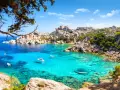 Turkusowa zatoka Costa Smeralda z łodziami i skalistym wybrzeżem.