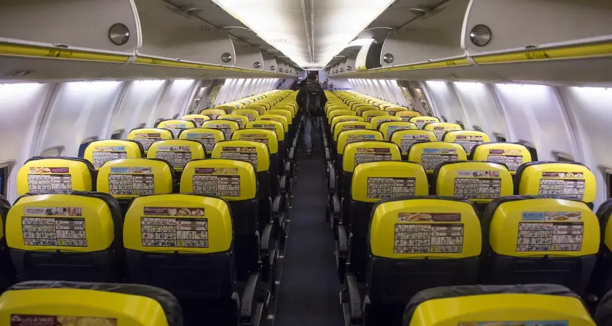 Puste rzędy żółtych siedzeń w samolocie Ryanair. Widać instrukcje bezpieczeństwa na oparciach.