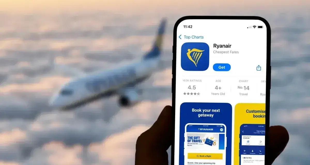 Ręka trzyma smartfon z aplikacją Ryanair, gotową do odprawy online. W tle widać samolot lecący wśród chmur.