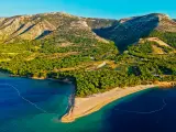 Idealne miejsce, gdzie na wakacje w lipcu: piaszczysta plaża w kształcie rogu obfitości, otoczona zielonymi wzgórzami i krystalicznie czystym morzem.