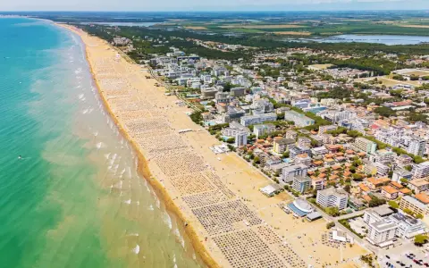 Słoneczna bibione plaża tętni życiem. Tysiące leżaków i parasoli tworzy barwny dywan, a turkusowe morze zaprasza do kąpieli.
