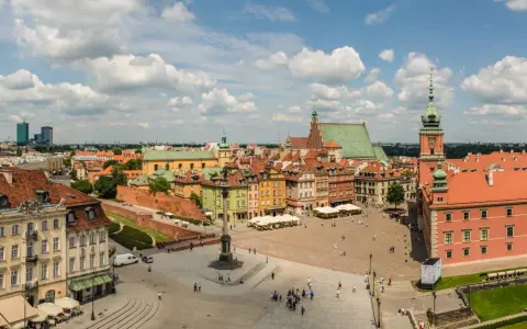 Uroczy city break z Warszawy. Rynek Starego Miasta tętni życiem, z kolorowymi kamieniczkami i Zamkiem Królewskim w tle.