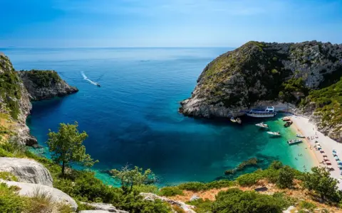 Malownicza zatoka z krystalicznie czystą wodą, plażą i łodziami. Idealne miejsce na wczasy samolotem all inclusive w Albanii.