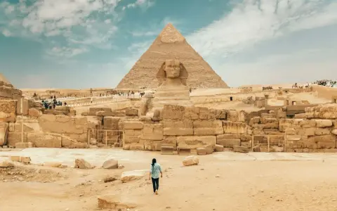 Piękna pogoda w Egipcie. Sfinks i piramida w Gizie, turystka idzie w ich stronę.