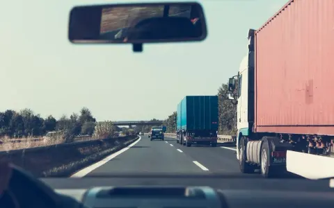 Jadąc autostradą, zastanawiam się, jakie kraje obejmuje zielona karta ubezpieczenia. W lusterku widzę inne ciężarówki.
