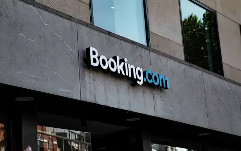 Logo Booking.com na szarym, kamiennym budynku. Planujesz podróż i szukasz najlepszych ofert? Z booking cashback Twoje wakacje będą tańsze!