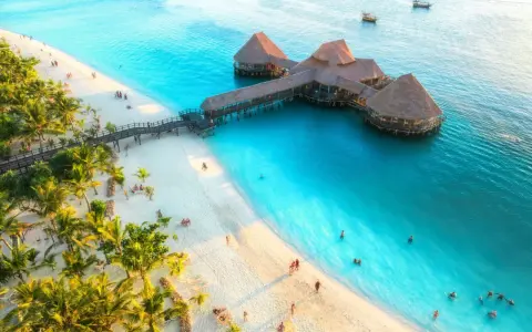 Rajska plaża na Zanzibarze z palmami i restauracją na wodzie. Sprawdź Zanzibar ceny, by zaplanować wymarzone wakacje.