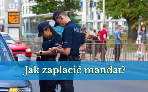 Dwóch policjantów w mundurach rozmawia, jeden z nich spisuje coś na kartce. W tle widać ludzi i budynki. Pytanie brzmi: "Jak zapłacić mandat?".