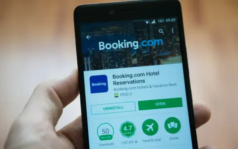 Telefon z aplikacją Booking.com. Użytkownik przegląda szczegóły, być może w celu zgłoszenia booking reklamacja.