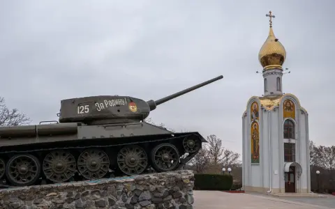 Czołg z napisem "Za Rodinu!" stoi obok cerkwi z złotą kopułą. Pomnik na nadniestrze.