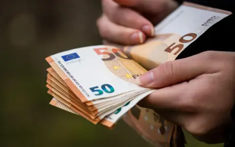 Dłonie trzymają stos banknotów 50 euro. Choć Bułgaria ma swoją walutę, euro jest powszechnie akceptowane.