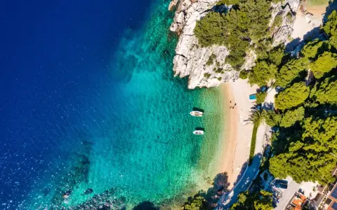 Chorwacja gdzie na wakacje? Rajska plaża z krystalicznie czystą wodą, łódkami i zielonymi wzgórzami. Idealne miejsce na relaks.