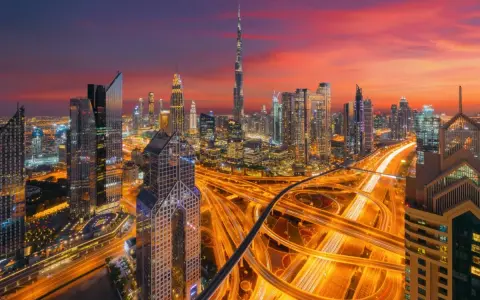 Wieczorny widok na Dubaj z drapaczami chmur i autostradą. W tle widać Burdż Chalifa. To miasto, gdzie kwitnie handel i **waluta Dubaju** jest symbolem rozwoju.