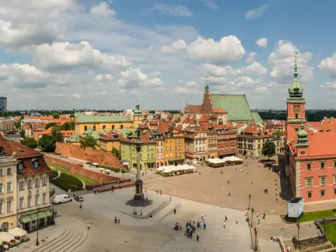 Uroczy city break z Warszawy. Rynek Starego Miasta tętni życiem, z kolorowymi kamieniczkami i Zamkiem Królewskim w tle.