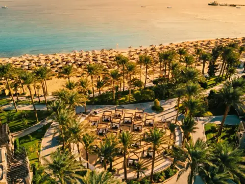 Rajska plaża w Makadi Bay z rzędami leżaków i palm. W oddali błękitne morze i statki.