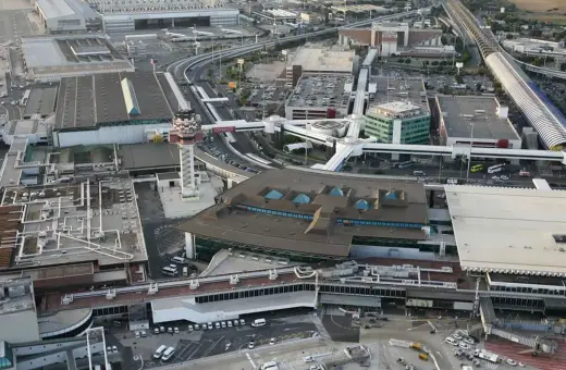 Widok z lotu ptaka na lotnisko Rzym Fiumicino. Widoczne terminale, wieża kontroli lotów, drogi kołowania i parkingi.