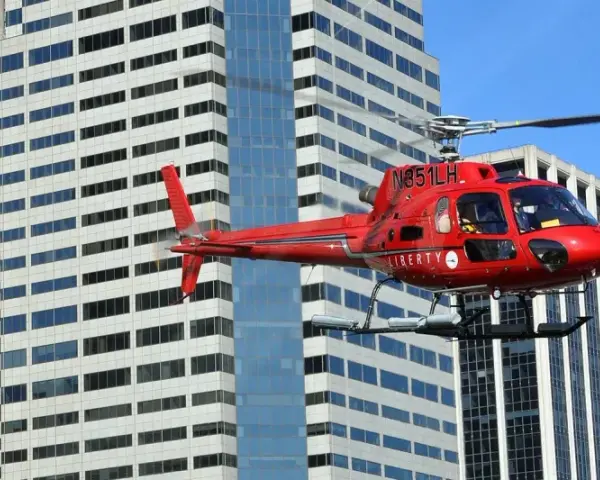 Czerwony helikopter Liberty przelatuje obok wieżowców. Zastanawiasz się, ile kosztuje lot helikopterem nad Nowym Jorkiem?