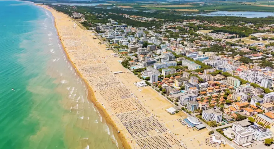 Słoneczna bibione plaża tętni życiem. Tysiące leżaków i parasoli tworzy barwny dywan, a turkusowe morze zaprasza do kąpieli.