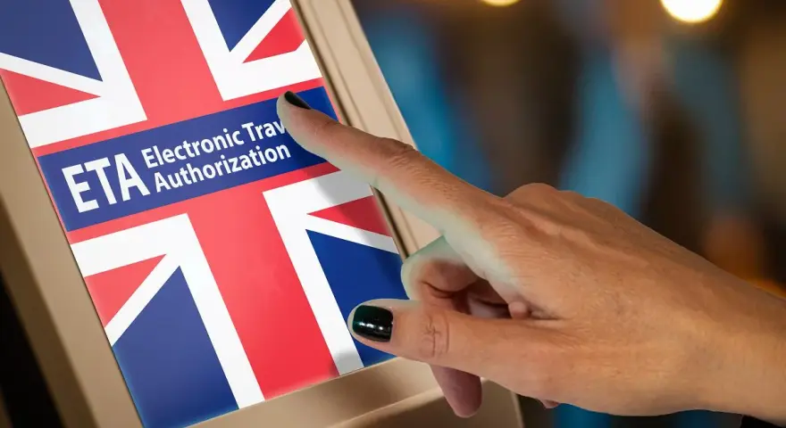 Palec dotyka ekranu z napisem ETA Electronic Travel Authorization i flagą Wielkiej Brytanii. Zastanawiasz się, ile kosztuje ETA do UK?