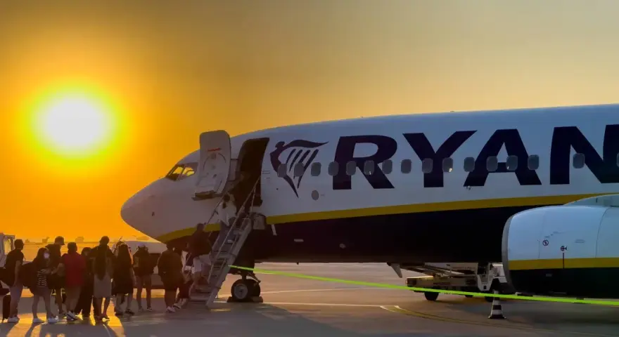 Ryanair loty za 1 zł – pasażerowie wsiadają do samolotu o zachodzie słońca.