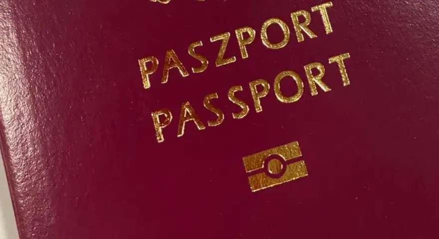Ciemnoczerwony paszport z napisem "PASZPORT" i symbolem. Numer paszportu jest ukryty.