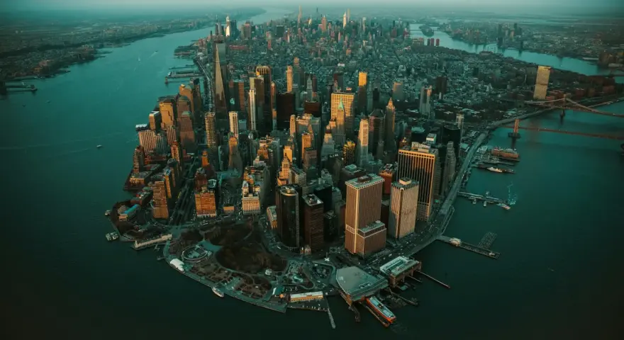 Zachód słońca nad Manhattanem, ta scena ukazuje panoramę drapaczy chmur i rzeki.