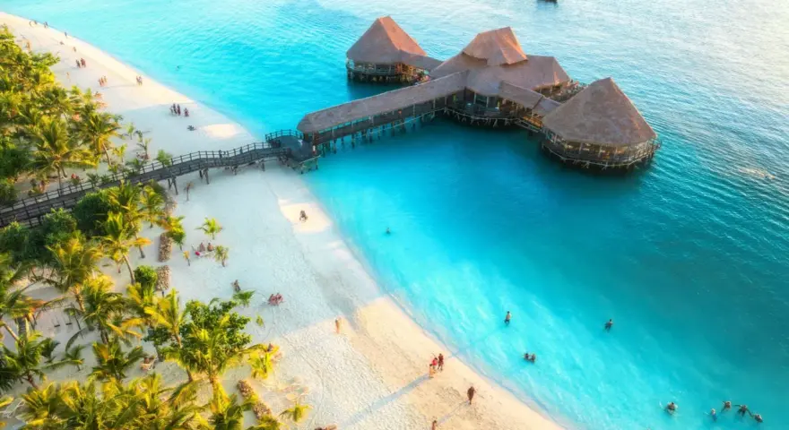 Rajska plaża na Zanzibarze z palmami i restauracją na wodzie. Sprawdź Zanzibar ceny, by zaplanować wymarzone wakacje.