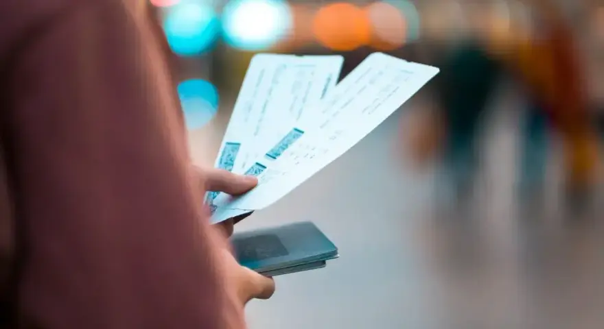 Dłoń trzyma bilety lotnicze i paszport. Może to być sytuacja związana z planowaniem podróży lub procesem **Ryanair zwrot biletu**.