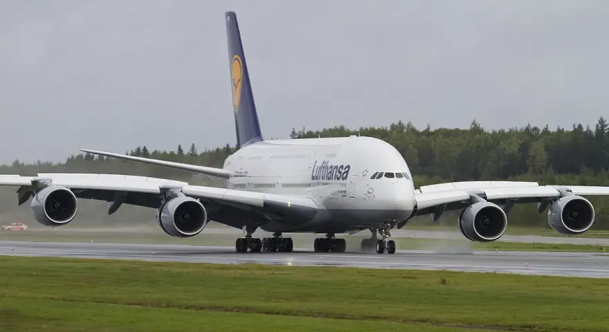 Lufthansa A380, największy samolot pasażerski, kołuje po mokrym pasie startowym.