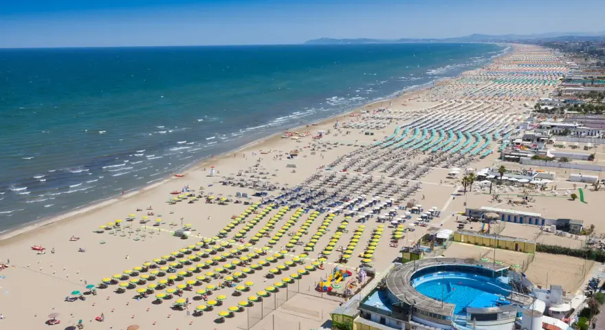 Słoneczna plaża w Rimini, pełna leżaków i parasoli, zaprasza na wakacje. Idealne miejsce na loty do Rimini!