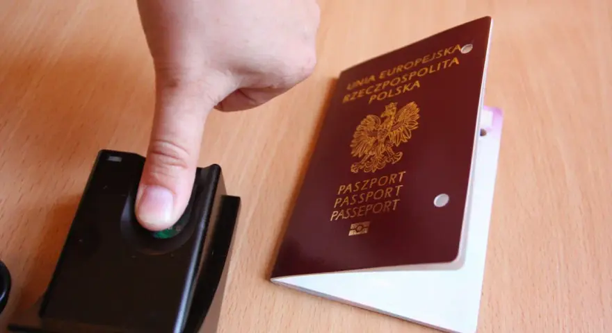 Palec na czytniku linii papilarnych obok polskiego paszportu. To pokazuje, ile ważny jest paszport w dzisiejszych czasach.