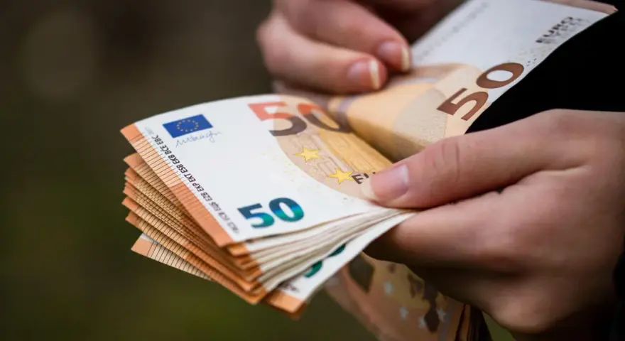 Dłonie trzymają stos banknotów 50 euro. Choć Bułgaria ma swoją walutę, euro jest powszechnie akceptowane.
