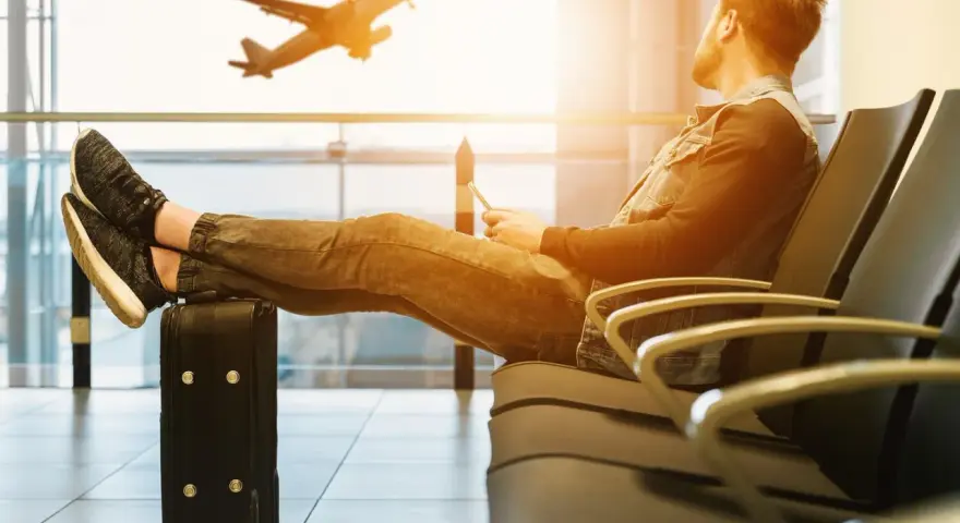 Mężczyzna czeka na lotnisku, nogi na walizce, samolot Wizzair startuje. Czyżby overbooking?