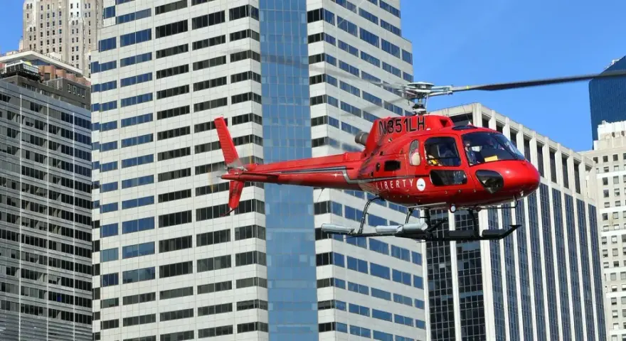 Czerwony helikopter Liberty przelatuje obok wieżowców. Zastanawiasz się, ile kosztuje lot helikopterem nad Nowym Jorkiem?