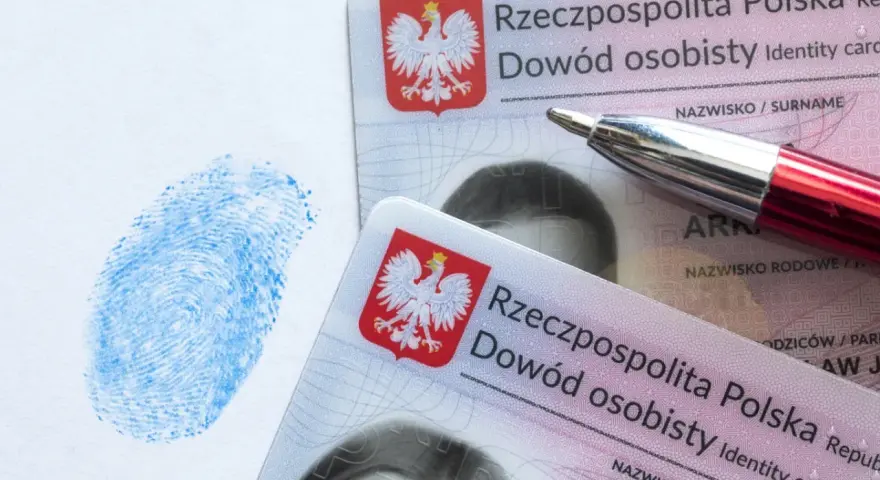 Dwa polskie dowody osobiste, niebieski odcisk palca i czerwone pióro. Dokumenty są kluczowe w procesie uzyskania serii dowodu osobistego.